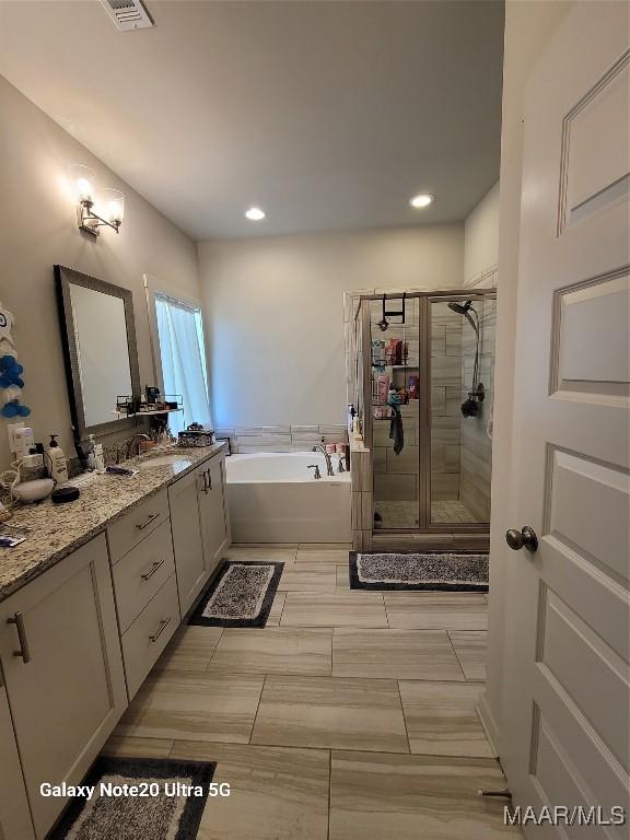 full bathroom featuring visible vents, recessed lighting, a shower stall, a bath, and vanity