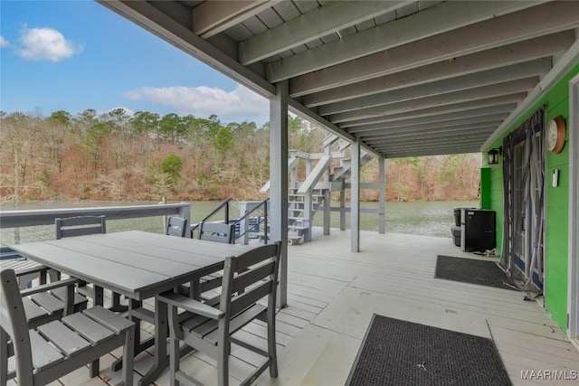 view of patio with stairs, outdoor dining area, and a water view