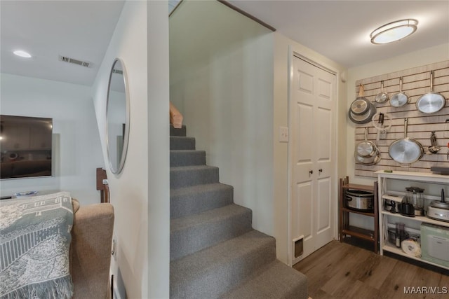 staircase with visible vents and wood finished floors