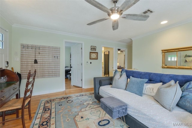 living area featuring visible vents, light wood-style flooring, a ceiling fan, crown molding, and baseboards