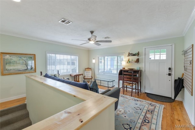 entrance foyer with visible vents, baseboards, ornamental molding, light wood-style floors, and a textured ceiling