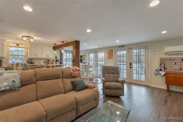 living area with wood finished floors, recessed lighting, french doors, and a wall mounted AC