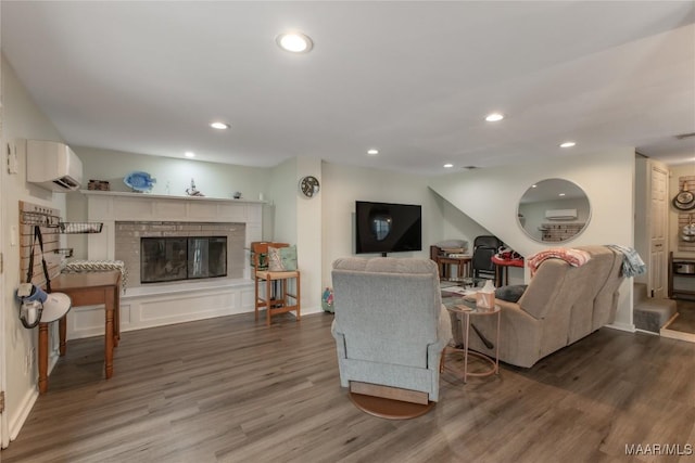 living room with a glass covered fireplace, wood finished floors, recessed lighting, and a wall mounted AC