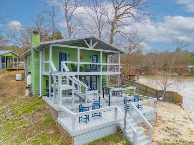 rear view of house with a chimney, stairs, a water view, and fence