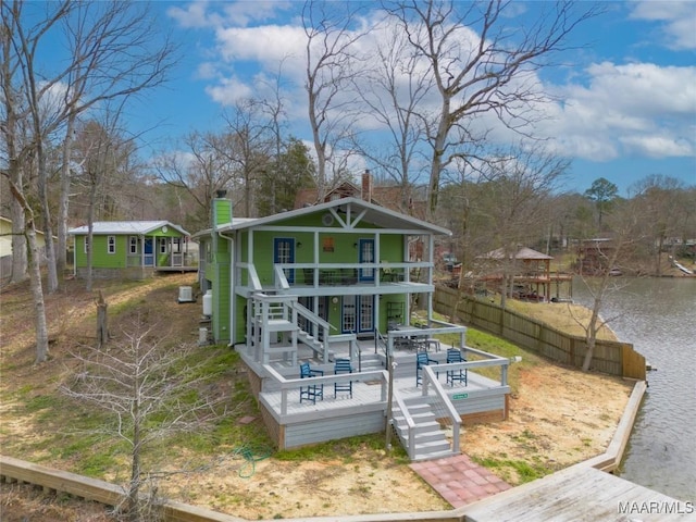 back of property featuring a deck with water view, a chimney, and fence