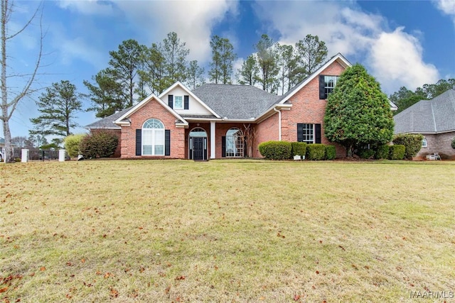 view of front of property featuring brick siding, roof with shingles, and a front lawn