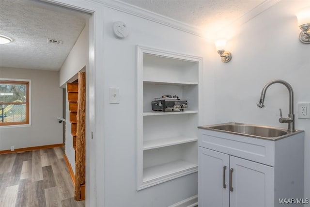 bathroom featuring visible vents, a textured ceiling, wood finished floors, baseboards, and vanity