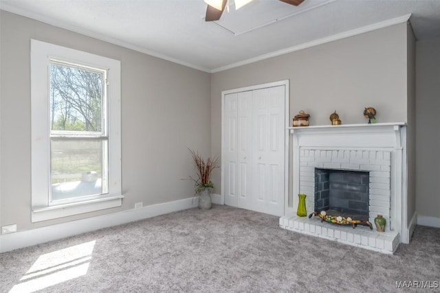 unfurnished living room featuring a ceiling fan, baseboards, crown molding, a brick fireplace, and carpet flooring