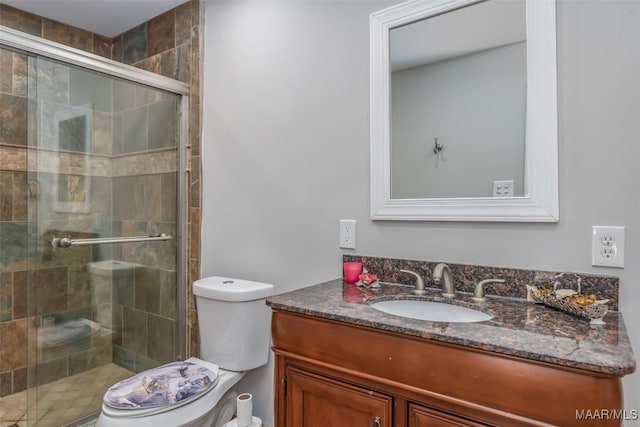 bathroom with a shower stall, vanity, and toilet