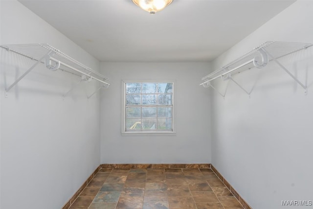 walk in closet featuring stone finish flooring