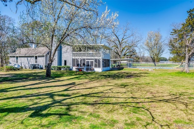 view of yard with fence, central AC, and a sunroom