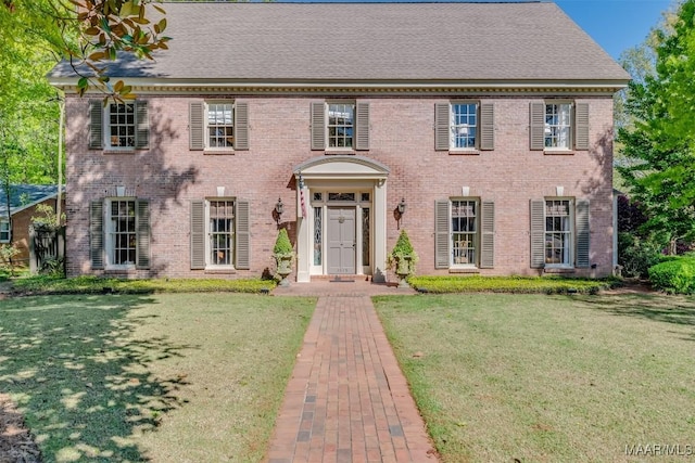 colonial home with a front yard and brick siding