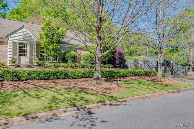 exterior space featuring entry steps, a front lawn, and brick siding