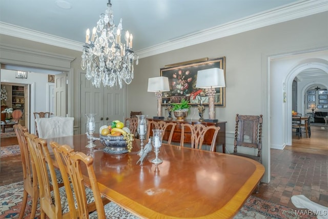 dining space featuring arched walkways, brick floor, an inviting chandelier, and ornamental molding