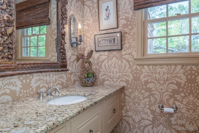 bathroom with wallpapered walls and vanity