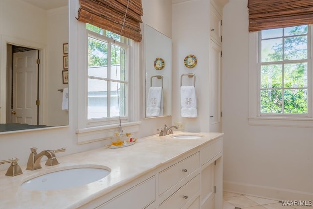 bathroom with double vanity, baseboards, tile patterned floors, and a sink