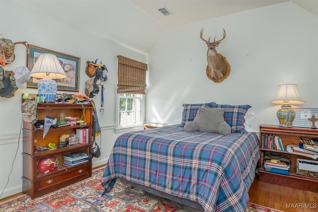 bedroom featuring vaulted ceiling, wood finished floors, visible vents, and baseboards