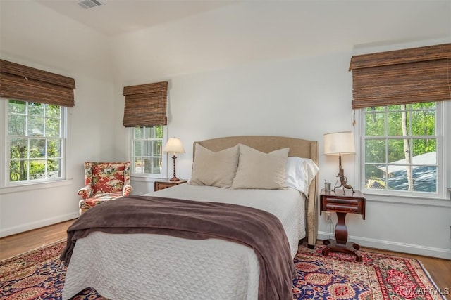 bedroom featuring visible vents, baseboards, and wood finished floors