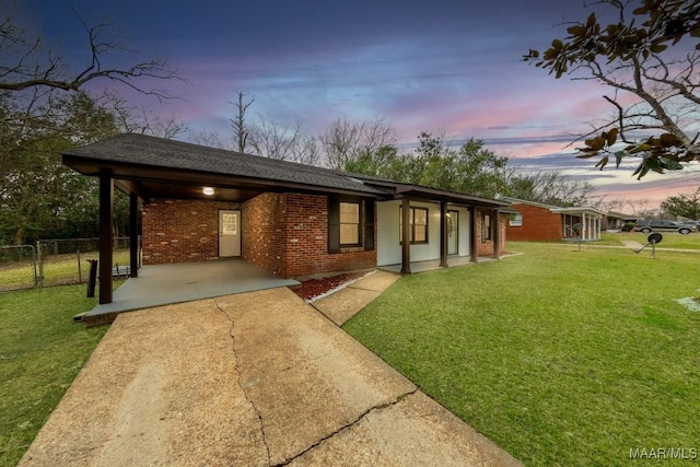 view of front of home featuring brick siding, fence, concrete driveway, a lawn, and a gate