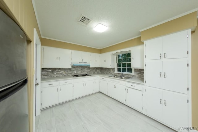 kitchen featuring visible vents, under cabinet range hood, freestanding refrigerator, electric stovetop, and a sink