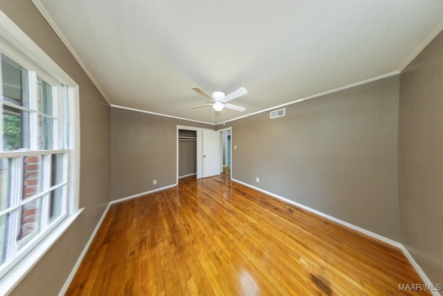 unfurnished room featuring visible vents, crown molding, baseboards, light wood-style floors, and a ceiling fan