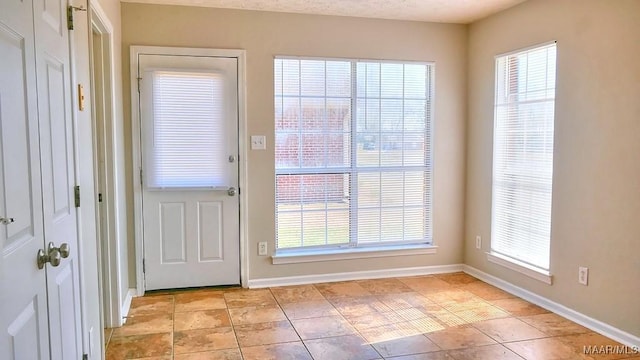 doorway to outside featuring light tile patterned floors and baseboards