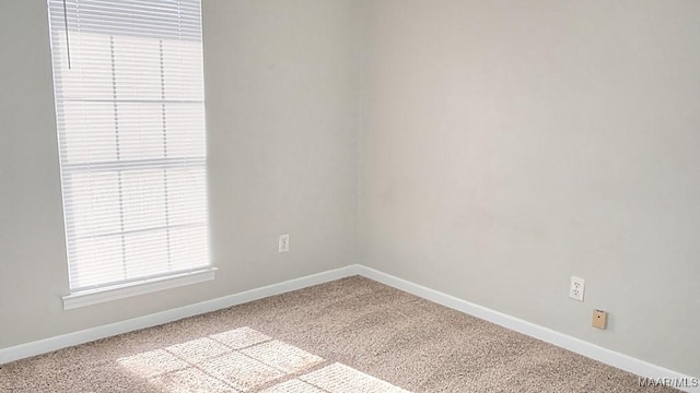 carpeted spare room featuring baseboards