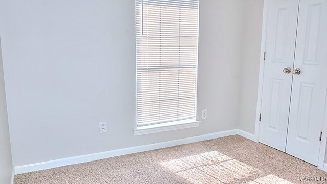 unfurnished bedroom featuring a closet, light colored carpet, and baseboards