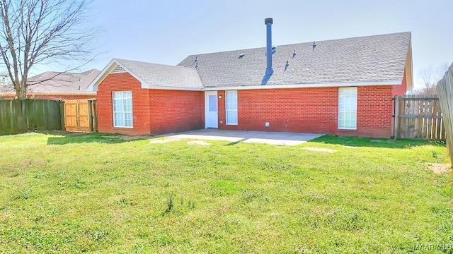 rear view of property featuring brick siding, roof with shingles, a fenced backyard, a yard, and a patio