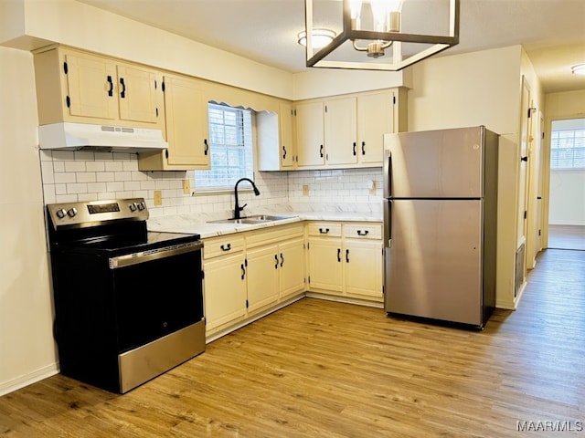 kitchen with under cabinet range hood, light countertops, light wood-style flooring, appliances with stainless steel finishes, and a sink