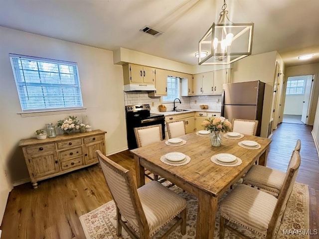 dining space featuring an inviting chandelier, wood finished floors, and visible vents