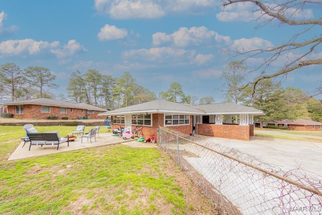 view of front of property with a front yard, fence, a patio area, and brick siding