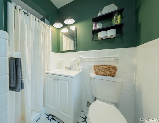 full bath with vanity, tile walls, toilet, and wainscoting