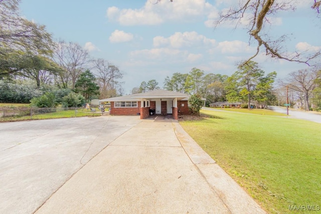 view of front of property featuring brick siding, concrete driveway, a front lawn, and fence