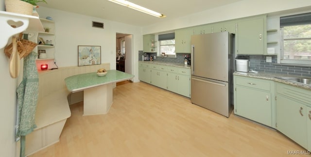 kitchen featuring open shelves, a healthy amount of sunlight, light wood-type flooring, and freestanding refrigerator