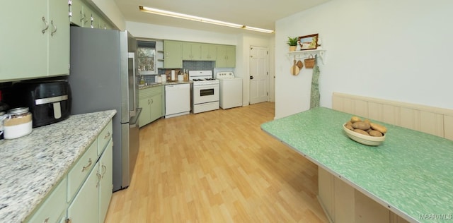 kitchen featuring white appliances, washer / clothes dryer, decorative backsplash, green cabinets, and light wood-type flooring