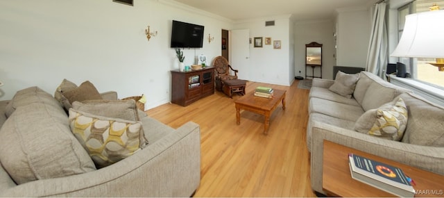 living room with visible vents, crown molding, and light wood-style floors