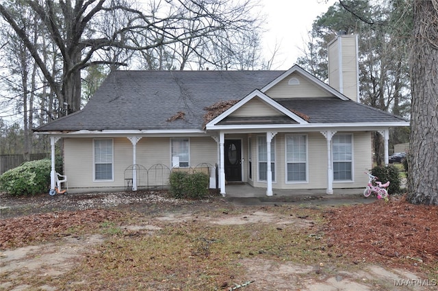 view of front facade with covered porch, a chimney, and a shingled roof