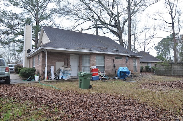 rear view of property featuring fence, brick siding, and a chimney