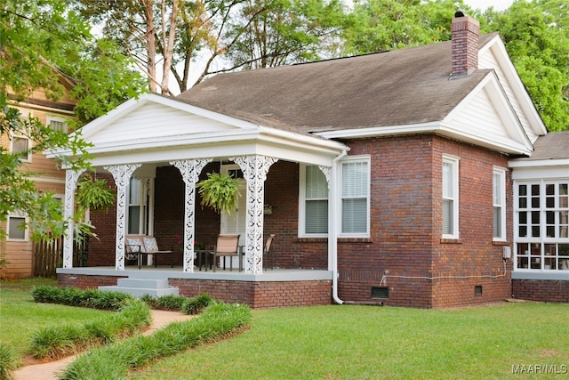 view of front of house featuring covered porch, a front yard, crawl space, brick siding, and a chimney