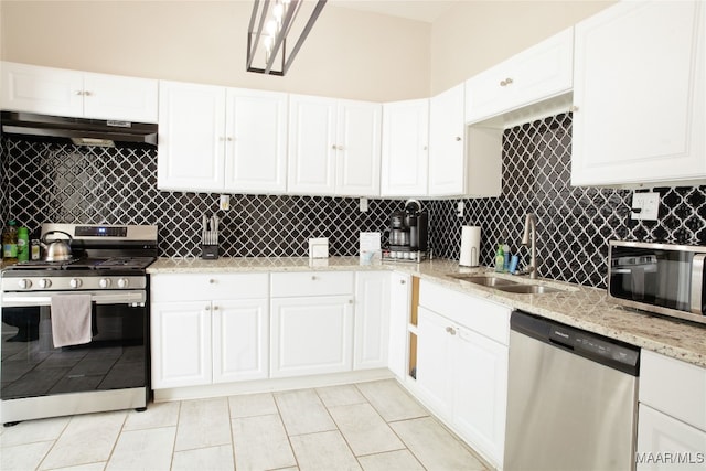 kitchen with light stone countertops, a sink, stainless steel appliances, under cabinet range hood, and tasteful backsplash