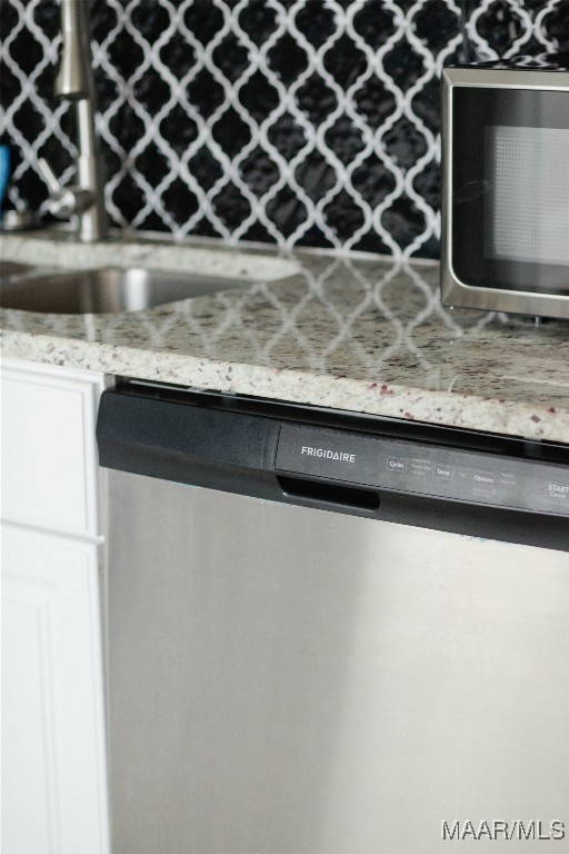 exterior details featuring white cabinets, light stone countertops, and stainless steel appliances