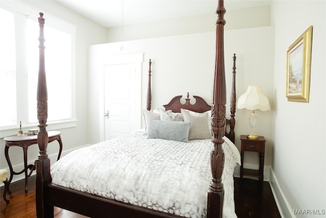 bedroom with dark wood-type flooring and baseboards