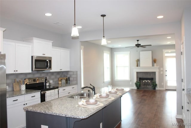 kitchen featuring a sink, backsplash, white cabinetry, appliances with stainless steel finishes, and a fireplace