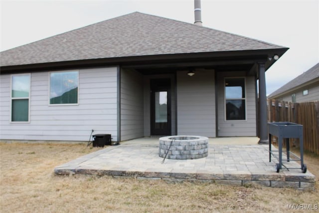 rear view of house featuring a patio, a fire pit, fence, and a shingled roof