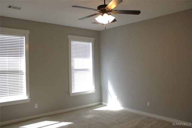 empty room with visible vents, baseboards, carpet, and a ceiling fan