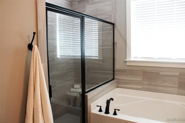 full bathroom featuring a bath and a shower stall