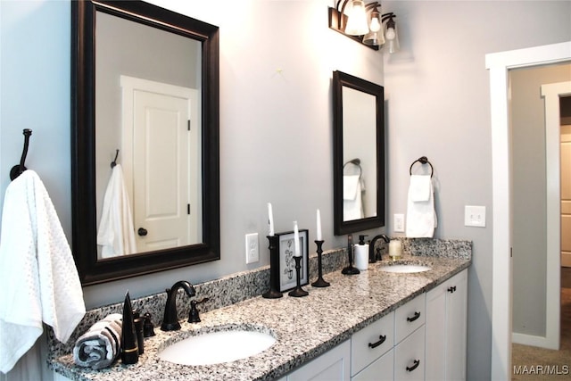 full bathroom with double vanity, baseboards, and a sink