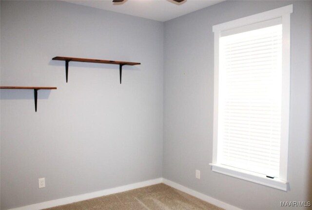 carpeted empty room featuring a ceiling fan and baseboards