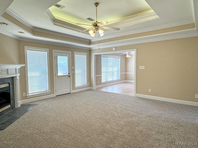 unfurnished living room with a tray ceiling, carpet, visible vents, and a tile fireplace